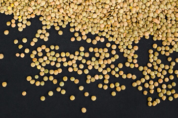 Dry green lentils on black surface, harvest concept