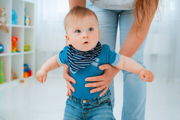 Baby taking first steps with mother's help at home