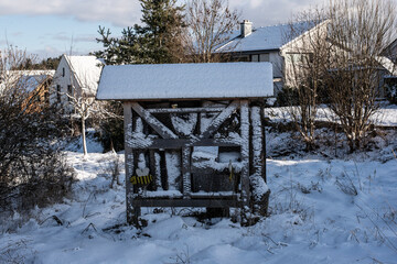 a wooden insect hotel in a snowy meadow