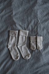 Cozy hygge socks for mom and newborn baby on grey linen cloth. Aesthetic minimalist baby fashion collage. Happy maternity concept