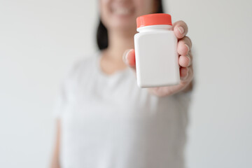 Woman hand holding white bottle free space for text healthcare and medical concept. Pill or supplement white bottle copy space to put your text.