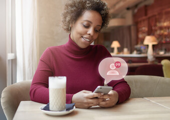 Portrait of influencer, african american woman sitting in cafe, checking followers on phone