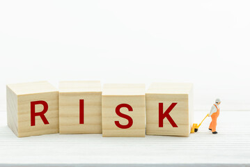 Risk assessment, risk analysis and management concept : Miniature messenger pulls, drags wood blocks with the word RISK, depict preparation for risk control and arrangement in investor asset portfolio
