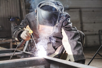 Male in face mask welds with welding