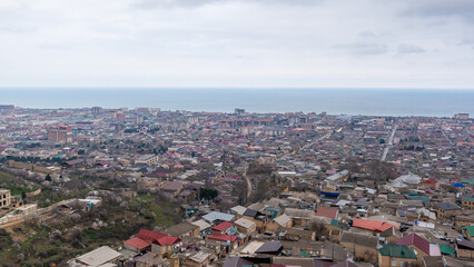 Old town along the blue sea, top view. The ancient city of Derbent in Dagestan with streets and houses is located next to the fortress.