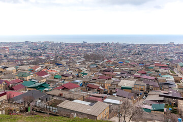 Fototapeta premium Old town along the blue sea, top view. The ancient city of Derbent in Dagestan with streets and houses is located next to the fortress.
