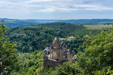 the historic Vianden Castle in Luxembourg in midst of lush green summer forest