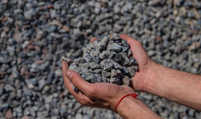 Crushed stones in the hands of a man. Selective focus.
