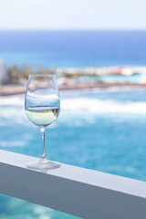 White wine glass on balcony with spectacular sea view in luxury hotel. Tropical vacation and summer time concept