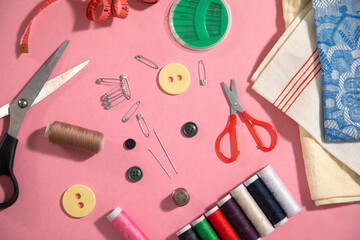 Fototapeta na wymiar Sewing tools on the pink paper background.