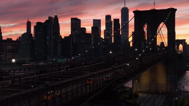 view of downtown NYC sunset descending alongside Brooklyn Bridge into Dumbo