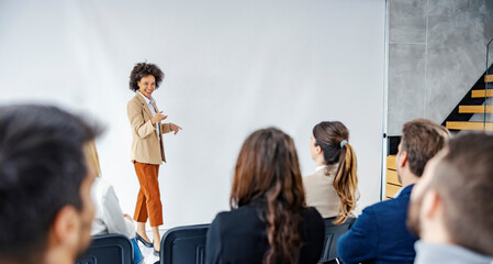 An African businesswoman having speech on seminar in front of the audience.