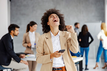 An african woman got a great news on the phone so she is celebrating.