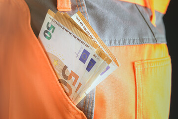 Good earnings. The builder got paid. Euro bills in the pocket of work pants. Close up