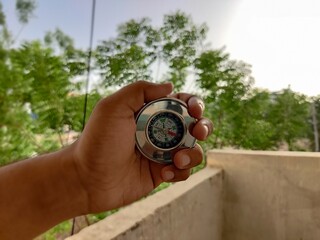 Naklejka premium Picture of a compass made of metal shot against blur background in summers during daylight used for directions by travelers 