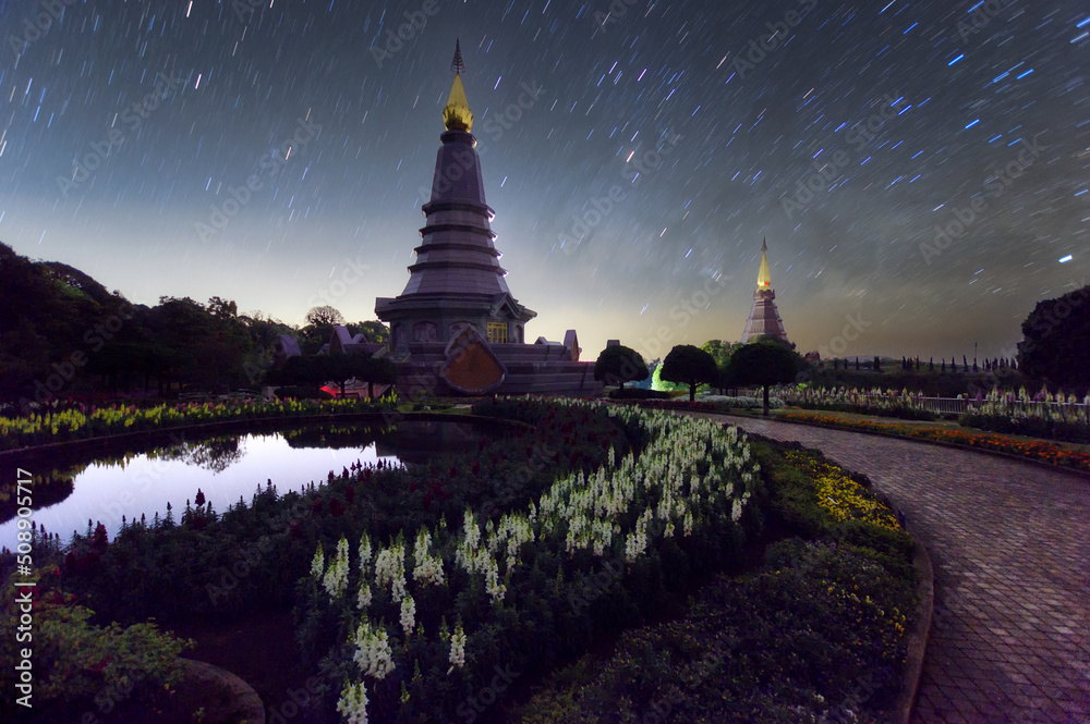 Wall mural star trails moving over a sacred temple at doi inthanon national park, chiang mai, thailand.