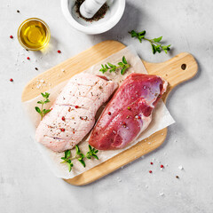 Preparation for cooking raw duck breast with ingredients. Light gray background, top view.