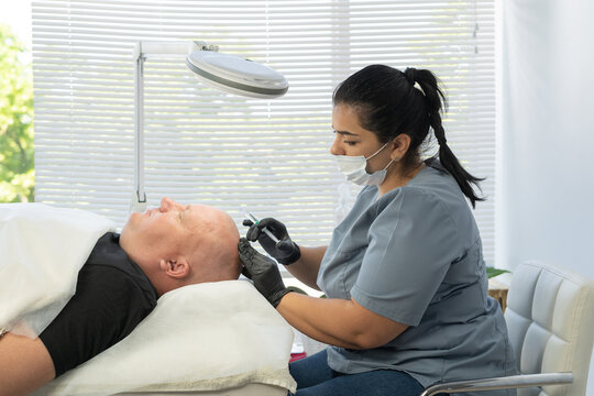 Close up of balding man getting hair mesotherapy or scalp prp. Platelet-rich plasma procedure. Cosmetologist doctor makes injections in the man head for hair growth