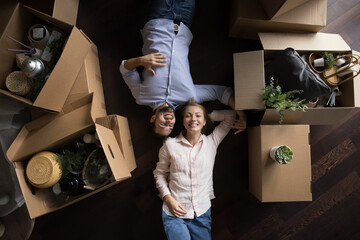 Beautiful couple in love lying on floor near heap of boxes with stuff resting on relocation or...