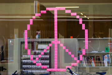 Peace sign at window of office room made of pink post it stickers at Swiss City of Basel on a sunny spring day. Photo taken May 11th, 2022, Basel, Switzerland.