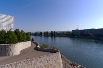 Facades of factory buildings with tree chimneys in backlight at industrial district of City of Basel with Rhine River on a sunny spring day. Photo taken May 11th, 2022, Basel, Switzerland.