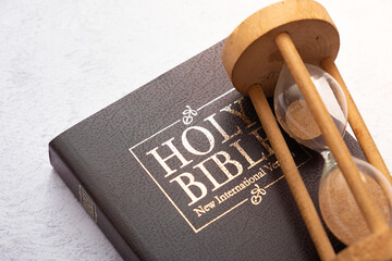 Top view of the Holy Bible on the desktop with hourglass. The concept of Bible study time