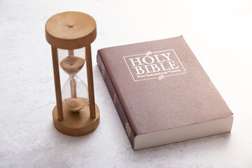 Top view of the Holy Bible on the desktop with hourglass. The concept of Bible study time