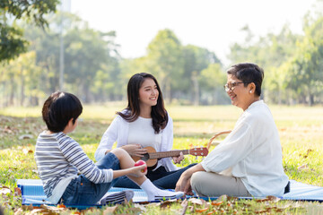 Group of Healthy multi generation Asian family enjoy picnic travel together at the park. Parents...