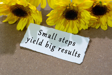 Motivational quote on torn white paper with sunflower on wooden table background