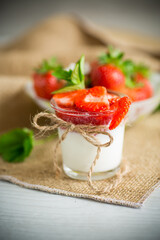 sweet homemade yogurt with strawberry jam and fresh strawberries in a glass cup