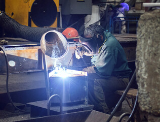 welder with welding machine and industrial hood at work