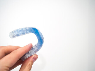 Hand holding mouthguard for bruxism problems with white copy space. Dental safety concept