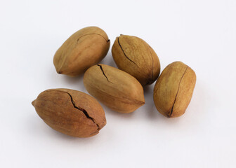 pecans in their shells on white background. A few unshelled nuts. Cracked nut shell