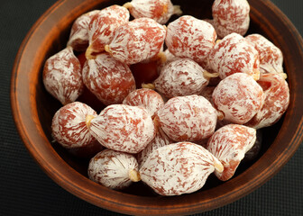 Mini round salami sausages in a brown bowl. chorizo mini spicy pork fermented dry cured salami...