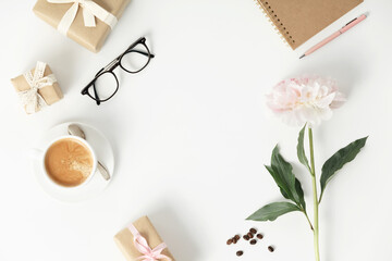 Festive arrangement: gift boxes, coffee, notebook, mobile phone, glasses and flowers  on a white table