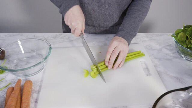 Curring vegetables on a white cutting board to cook vegetarian white bean soup.