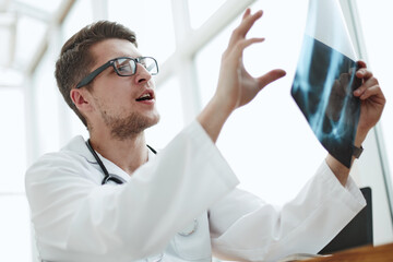 Male doctor radiologist examines x-rays in a medical office.