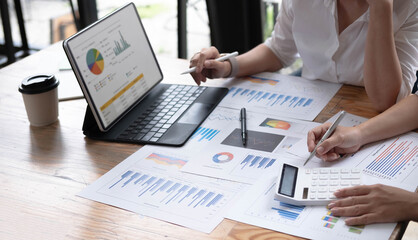 Two women analyzing documents while sitting on a table in office. Woman executives at work in office discussing some paperwork.