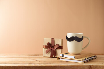 Father's day concept with coffee cup, mustache, notebook and gift box over beige background