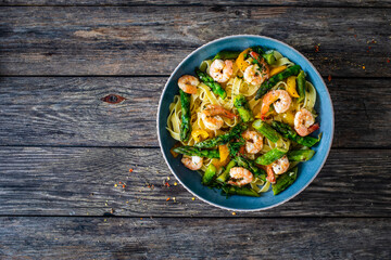 Tagliatelle with prawns and asparagus on wooden table

