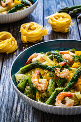 Tagliatelle with prawns and asparagus on wooden table

