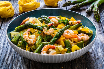 Tagliatelle with prawns and asparagus on wooden table
