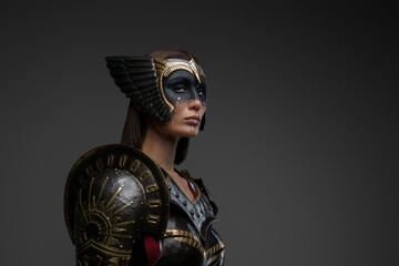 Portrait of attractive woman warrior with painted face dressed in dark steel armor.