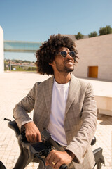 Contented African American man riding bicycle. Male model with curly hair in suit with modern bicycle. Active lifestyle concept