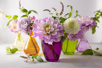 Autumn still life with bouquets of flowers in multicolored vases on table. Autumn floral decoration for home.