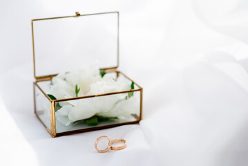 wedding gold rings on the background of a glass box on a background of white fabric. concept for event agencies