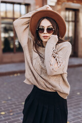 BEAUTIFUL YOUNG GIRL IN SUNGLASSES AND A BED HAT ON THE CITY STREET