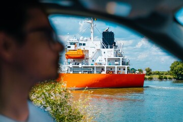 Man driving car by ship on river