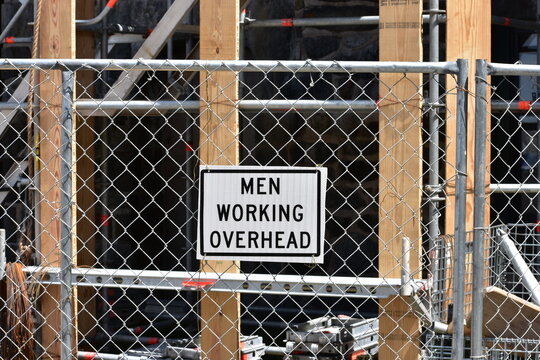 Men working overhead construction warning sign