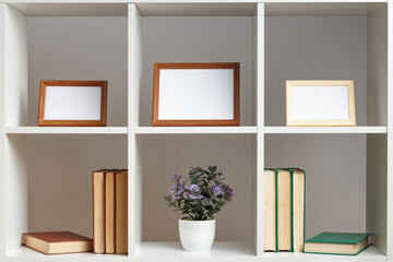 White shelves photo frame books potted plant. Home interior, decor elements.
